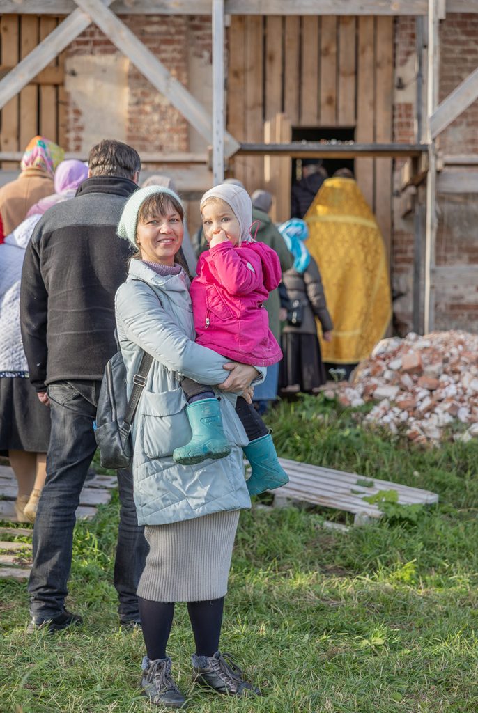 Лена держит Катю на руках у храма.