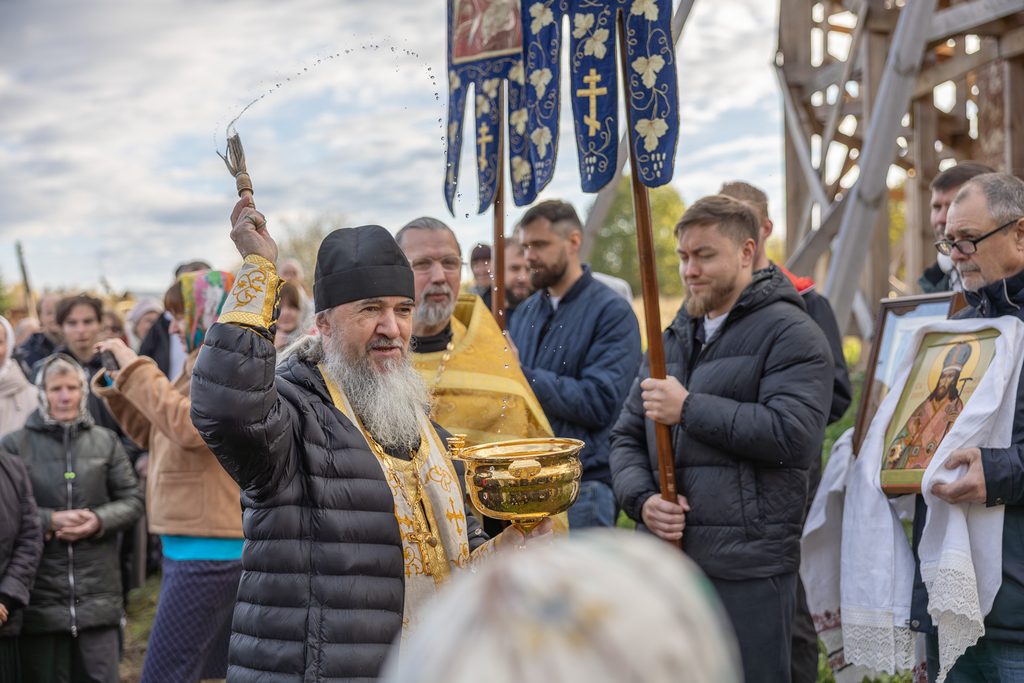 Отец Михаил окропляет участников крестного хода святой водой.
